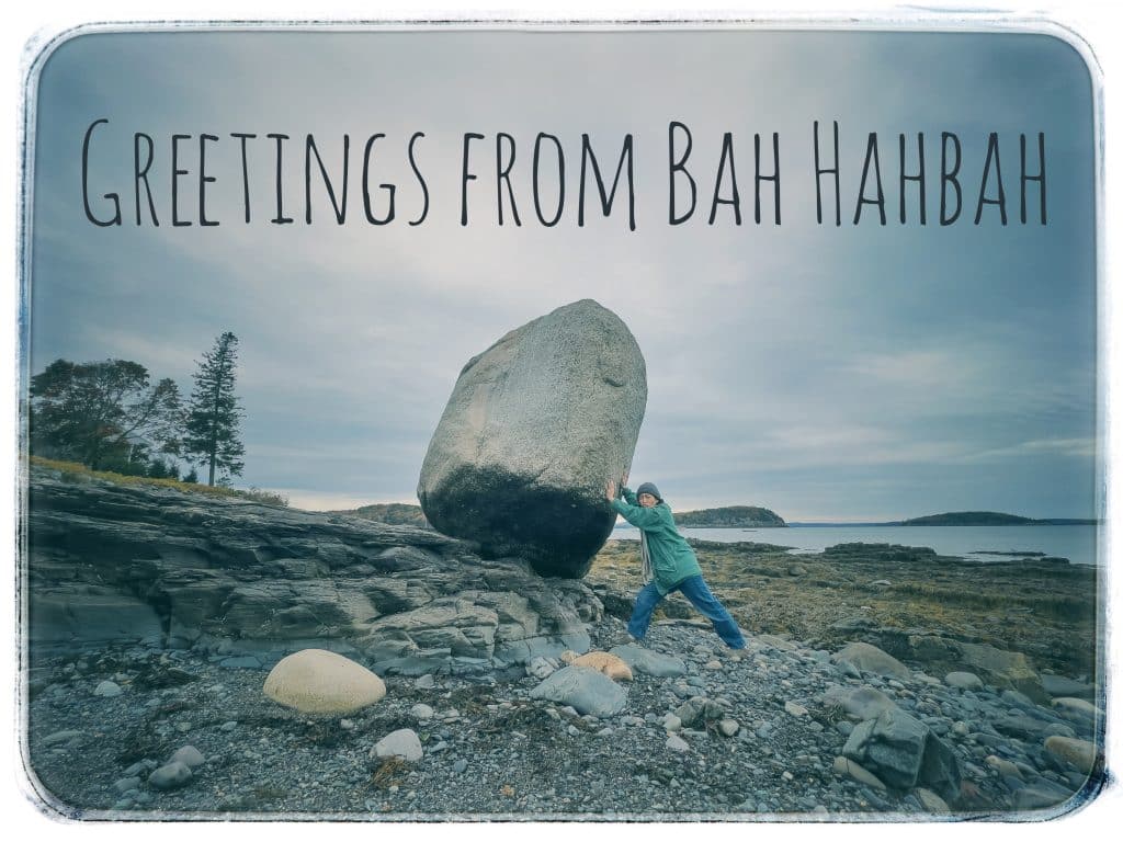 Photo of a postcard example of the balance rock with a person pretending to hold it up or push it. It reads "Greetings from Bah Habah"